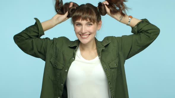 Slow Motion of Silly and Cute Female Model Playing with Two Ponytails Hairstyle and Smiling Having