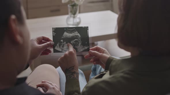 Lesbian Couple Holding Baby Ultrasound Image alt