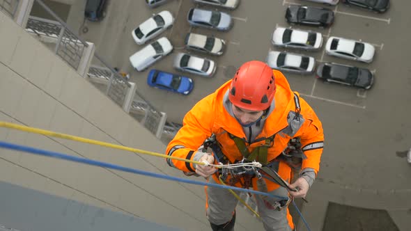 Industrial Climber in Suit Sets Up Protector Protect Against Abrasion of Rope When Descending From alt