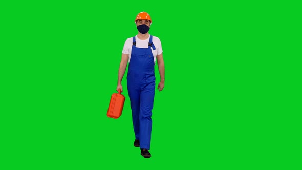 Builder in Protective Mask and Hardhat Walking with Red Case on Green Screen
