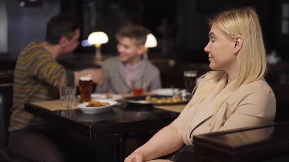 Portrait of Embarrassed Woman Turning Looking at Camera Gesturing As Cheerful Husband and Son Having alt