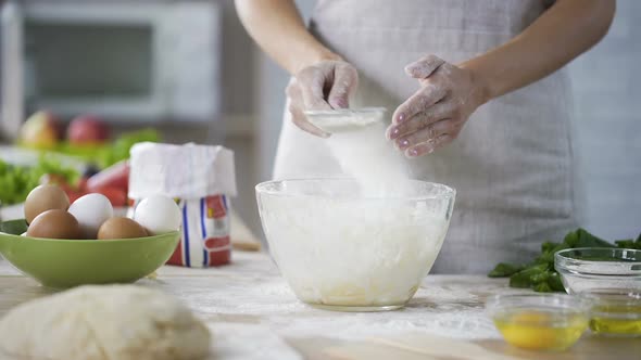 Closeup of Woman Hands Sieving Flour Over the Glass Bowl With Dough, Bakery alt