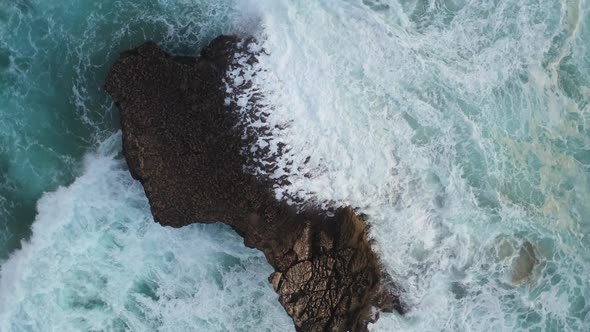 Praia Do Tonel rock formation battered by ocean waves, Cape Sagres Portugal, Aerial rising rotation alt