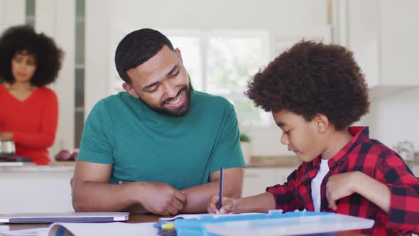 Father helping son with homework at home alt