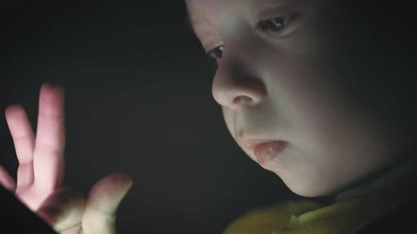 Little Boy, Sitting in a Dark, Playing with Smartphone. Cute Boy Using a Smartphone, Resting on a alt