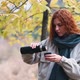 Beautiful Redhaired Woman Drinks Tea From Thermos in the Autumnal Forest