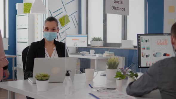 Coworkers with Protection Face Masks Working Together in New Normal Office alt