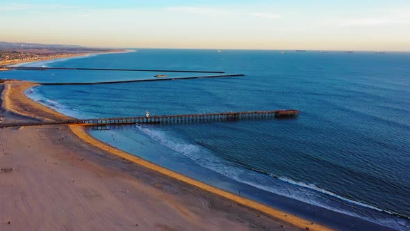 Seal Beach Pier slowly flying away with views of the beach and pacific ocean. alt