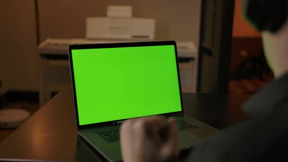 Caucasian Male in Headphones Listening Music Behind Green Screen Laptop alt