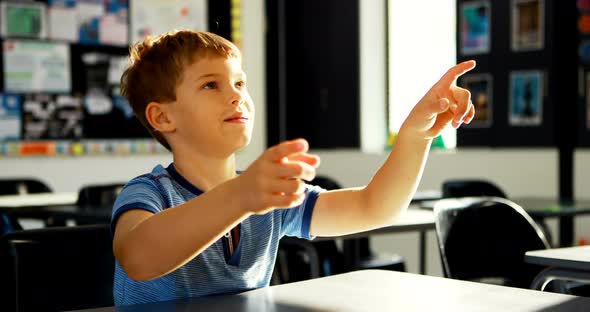 Schoolboy pretending to touch an invisible screen in classroom 4k alt