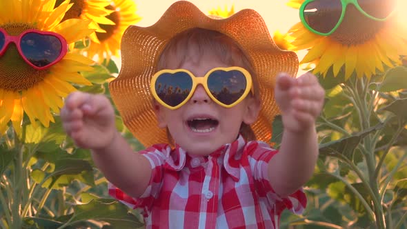 Happy child having fun in spring field of sunflowers. Slow motion