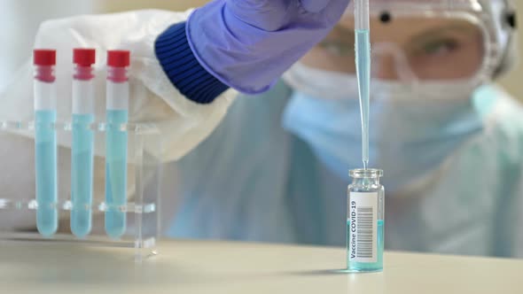 Professional Female Scientist in Protective Eyeglasses and Mask Making Experiment with Reagents in alt