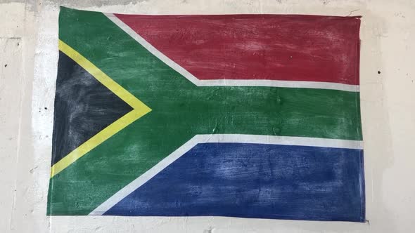 hand held close shot of a hand painted national flag of the Republic of South Africa on a white wall alt