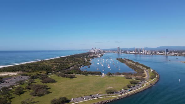 High fasting drone view travelling over a man-made island towards a popular urban boat harbor with a alt