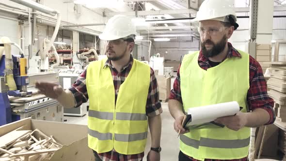Two Workers in Reflective Waistcoats and Helmets at the Furniture Factory alt