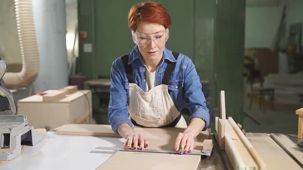 Female Carpenter in Blue Shirt Drawing Line with a Measurement Tool on Wooden Plank