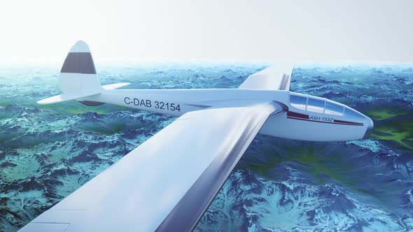 The white sailplane calmly gliding in the sky over the snow-covered mountains. alt