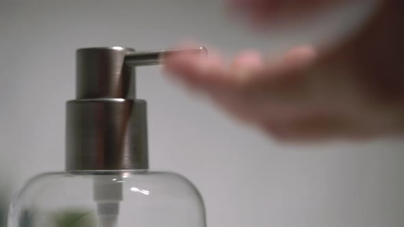 A Woman Uses a Dispenser with Antibacterial Soap or Antiseptic