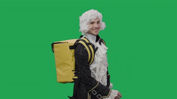 Portrait of Courtier Gentleman in Black Vintage Suit and Wig Walking with Large Yellow Backpack alt