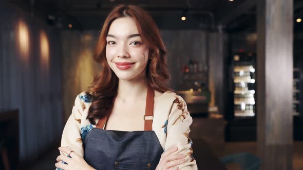 Business owner attractive young asian woman in apron hanging we're open sign. alt