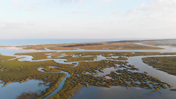 Tracking drone footage over wetlands towards a beach at sunset in SC alt