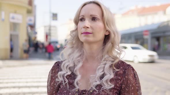 A Middleaged Caucasian Woman Looks Around in Puzzlement in an Urban Area alt