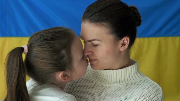 Young Woman with Her Daughter on the Background of the Flag of Ukraine