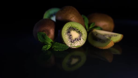 Fruits of Juicy Kiwi Rotate on a Table on a Black Background alt