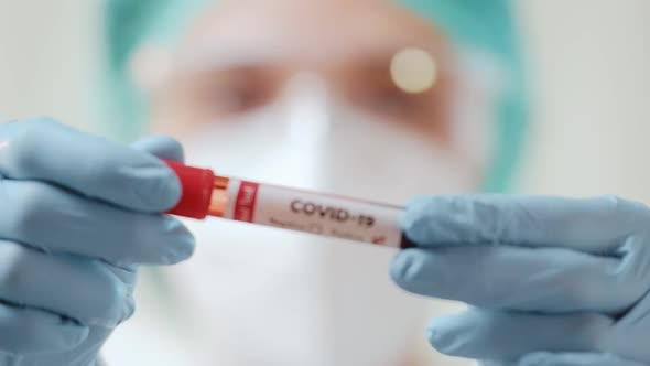 Female Doctor Holds a Blood Test Tube To Check a Blood Sample for the COVID-19 Virus. alt
