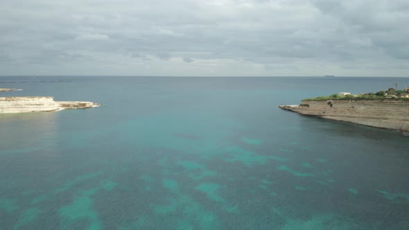 AERIAL: Ta Kalanka Sea Cave Bay with Cloudy Sky and Beautiful Turquoise Color Water