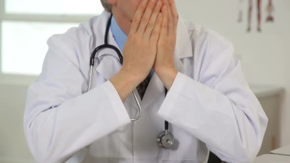 Upset doctor with head in hands alt