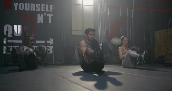 muscular athletic group doing training abdomen exercises working out with a medicine ball