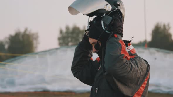 Man Putting on Helmet with Windshield and Communication Equipment alt