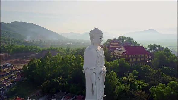 Drone Passes Large White Buddha Statue and Moves To Temple alt