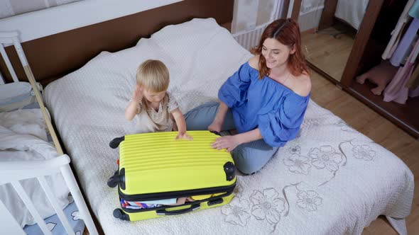 Vacation Preparation, Young Respectable Female Parent and Her Own Male Child Have Fun Packing 