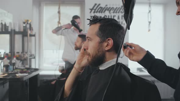 Man Talking on Phone Having His Hair Dried and Groomed in Barbershop alt