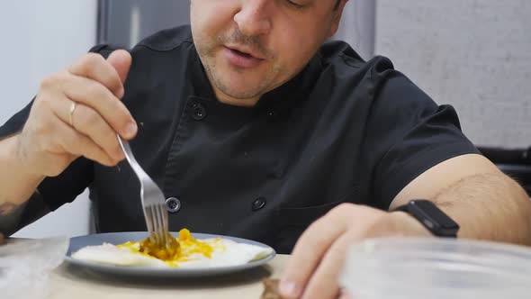 a Young Man in a Black Jacket Eats Eggs with a Fork and Laughs alt