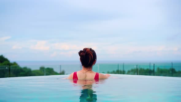 Young woman traveler relaxing and enjoying by a tropical resort pool while traveling