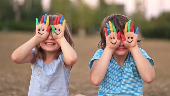 Two Funny Sisters Smile and Waving Painted Hands in Summer alt