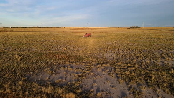 Isolated red truck parked in the middle of farm fields in a large agricultural field in the USA. Aer alt