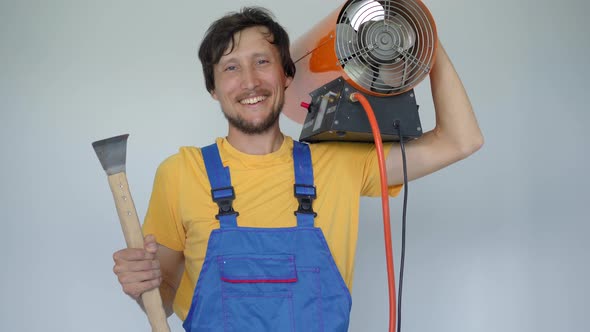 A Man Professional Home Renovator Holds a Propane Hot Air Heater and a Hook for Stretch Ceiling alt