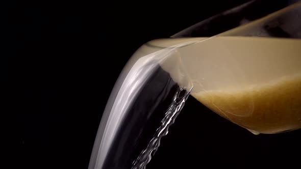 Washing rice, water pours from a bowl on a black background. Slow motion. alt