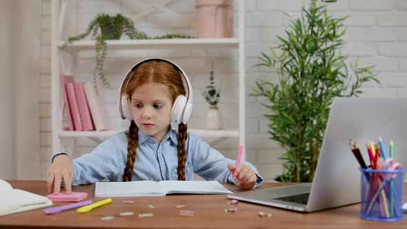Little Child Girl Using Laptop for Doing School Tasks at Home and Writing Notes.