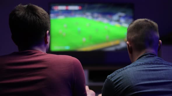 Friends Having Fun on Evening Playing Football Video Games With Excellent Mood in Modern Living Room