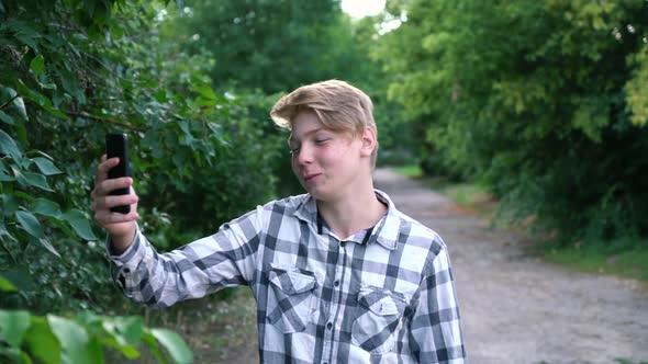 a Young Teenager Man of Caucasian Ethnicity in a Gray Shirt in a Cage Stands on the Street in the alt