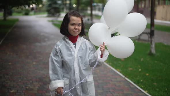 Portrait of Smiling Little Woman Posing with Balloons in Slow Motion Outdoors alt