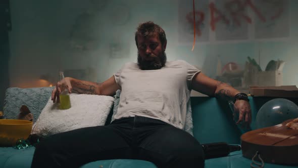 Man Drinking Alcohol on Sofa in Smoky Room alt