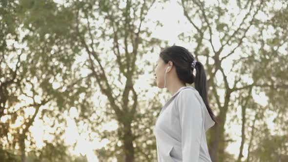 Attractive young Asian female runner walking seaside relaxing on the beach after running.