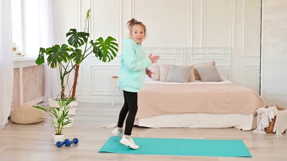 Happy Child Dancing in the Living Room on a Sports Mat Long Hair the Girl Feels Good and Excited
