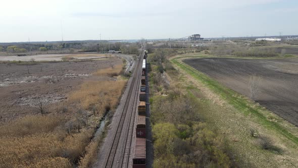 Freight train holding on tracks in countryside. Grain elevator seen in the background.